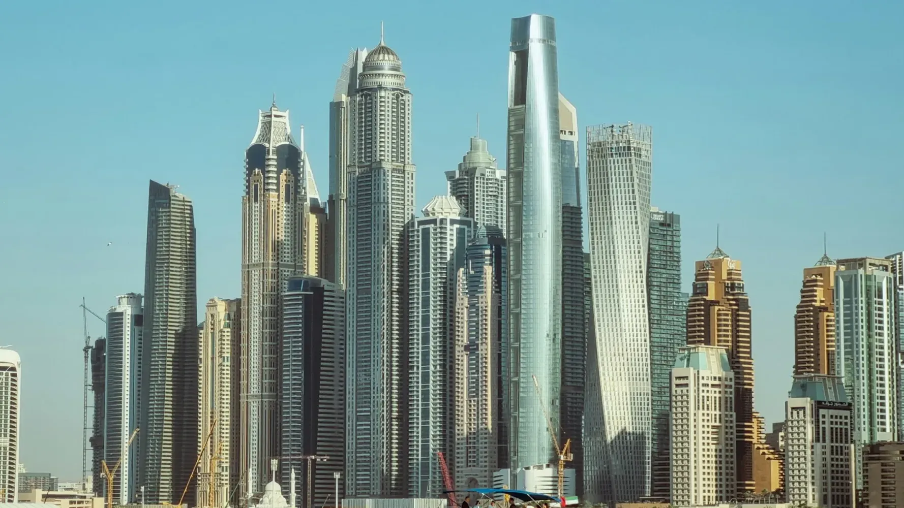 Modern skyscrapers of Dubai Marina against a clear blue sky, showcasing futuristic and diverse high-rise architecture.