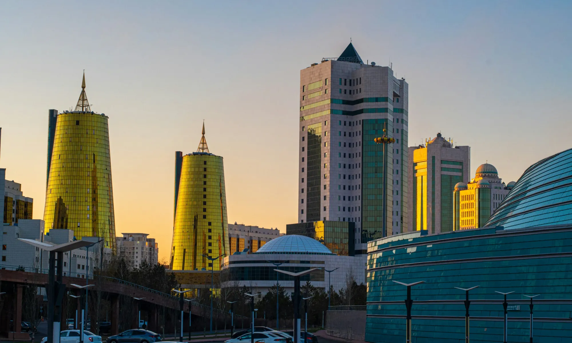 Modern skyline of Astana, Kazakhstan, with golden towers and government buildings at sunset.