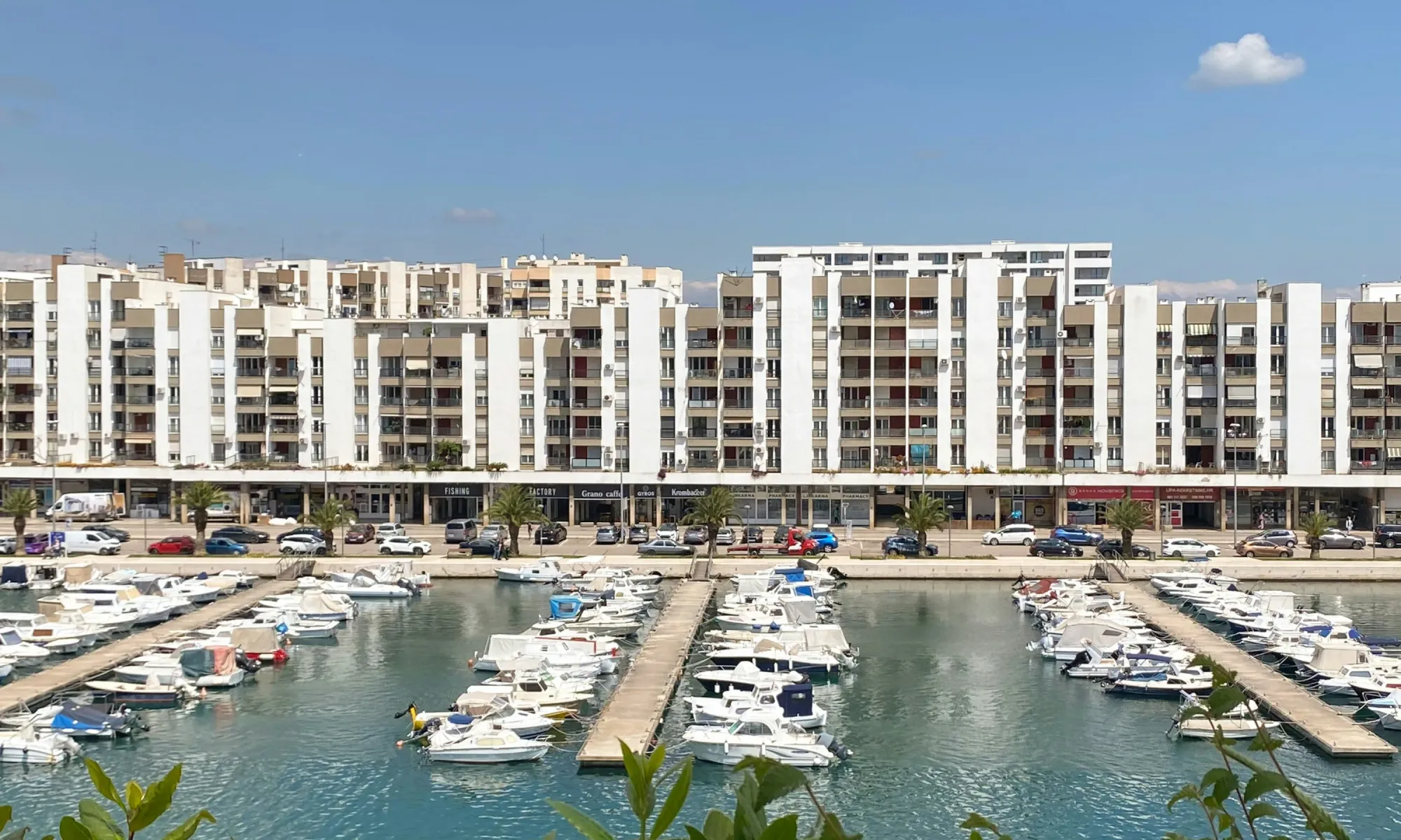 Modern apartment buildings in Split, Croatia, with a marina full of small boats in the foreground.