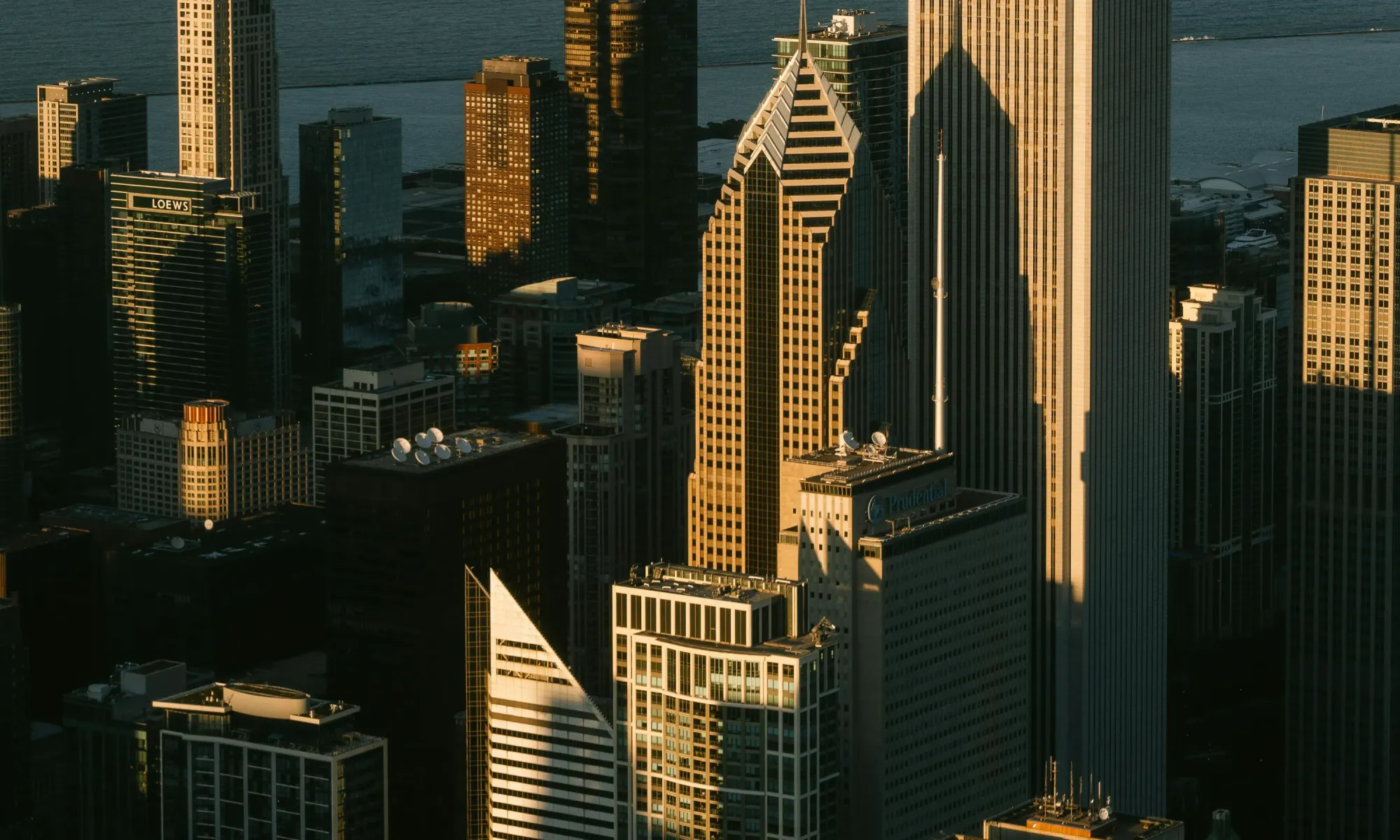 Downtown Chicago skyline with tall skyscrapers, including Prudential and Loews buildings, lit by golden sunset light.