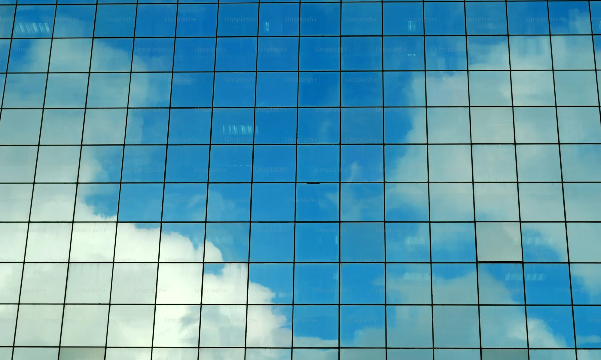 Modern glass office building reflecting sky — real estate technology