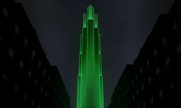 Dark night scene: a tall, tiered skyscraper outlined in vivid green light rises between shadowed mid-rise buildings under a cloudy sky.
