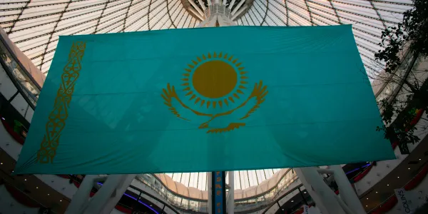 Large Kazakhstan national flag displayed indoors under a glass dome.